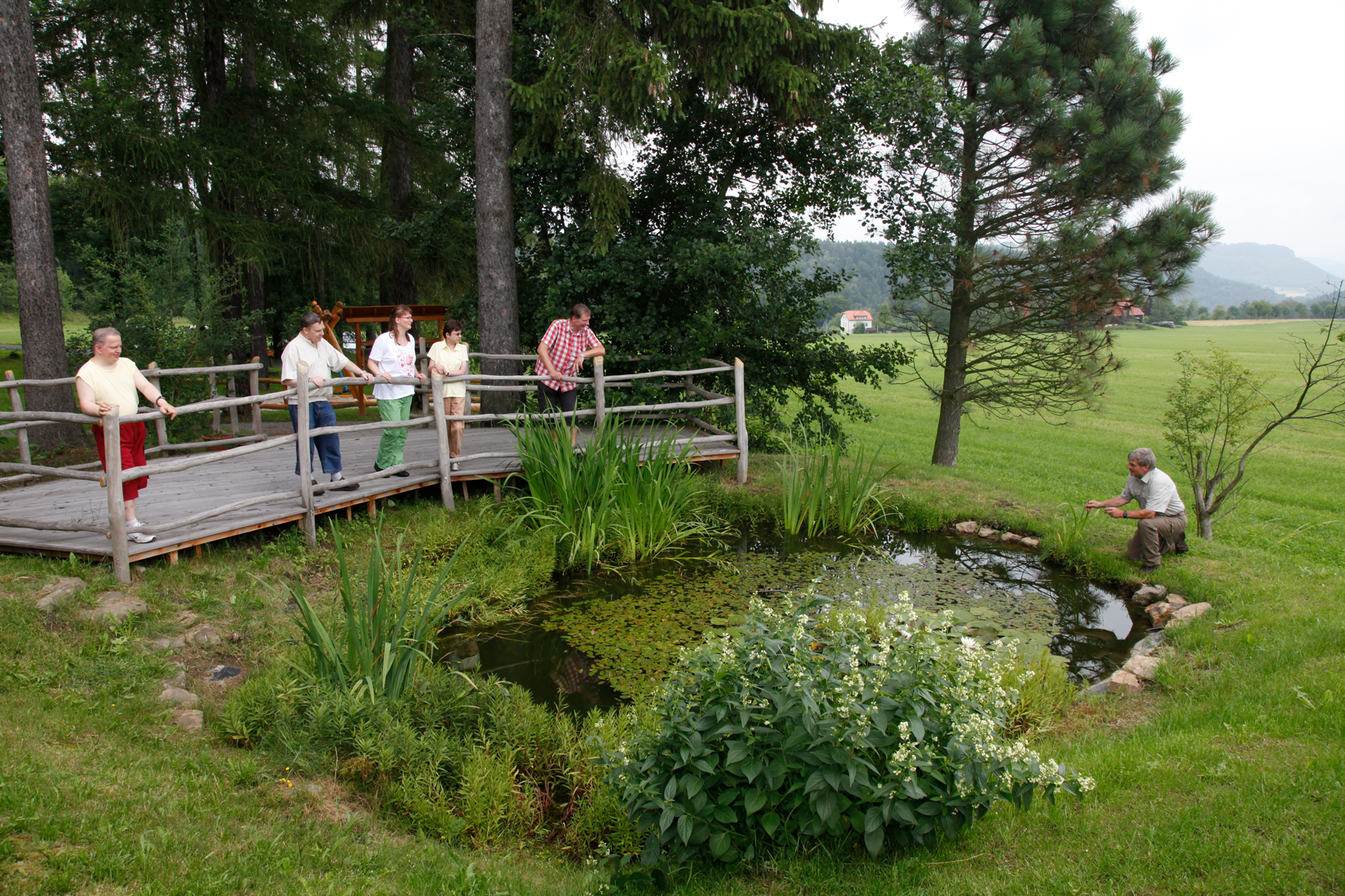 Besucher blicken von einer Plattform aus auf den Teich.